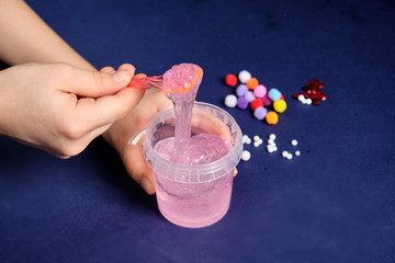 We make slime at home. making popular children's toys from glue.. Children's hands make a toy out of slime on a blue background.
