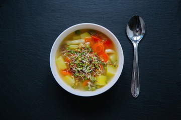 Vegetable soup in a bowl isolated on dark background. Top down view.