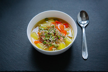 Vegetable soup in a bowl isolated on dark background. Top down view.