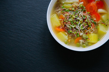 Vegetable soup in a bowl isolated on dark background. Top down view.