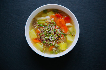 Vegetable soup in a bowl isolated on dark background. Top down view.