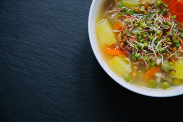 Vegetable soup in a bowl isolated on dark background. Top down view.