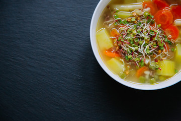 Vegetable soup in a bowl isolated on dark background. Top down view.
