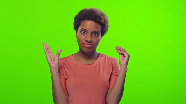 A young dark skinned woman doesn't want to listen anymore and shows blah blah gesture hands symbol of speaking mouth, poses against chromakey background. People, beauty and hand gesture concept