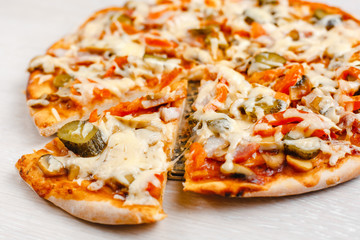 Italian pizza with bacon and pickles, mushrooms, capers and Parmesan cheese. Side view, top view. On a light table. Space for text