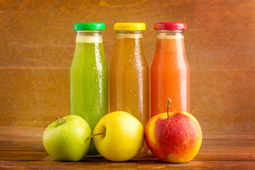 apple fresh juice from green, red and yellow apples on wooden background