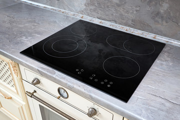 Modern kitchen interior with black induction or electric hob stove cooker with ceramic top surface...