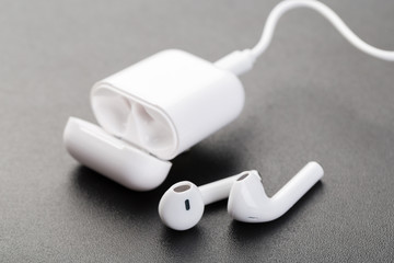 Modern wireless bluetooth headphones with charging case on a dark black background.