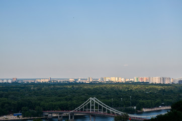 Cable-stayed pedestrian Park bridge to Trukhanov island across Dnieper river and panorama of the left bank in Kiev, Ukraine 