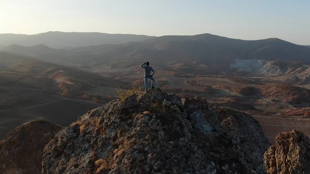 Brave stranger at the top of the rock watching the beautiful sunset over the valley Inspirational decision fill the expectations