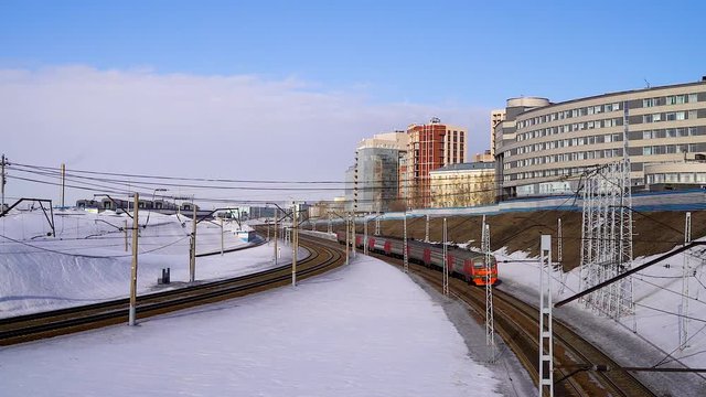 The train passes under the bridge and is removed. Railway in winter, the view from the top.