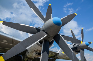 Two big airplane propeller blade of engine on one side of the plane and blue sky with clouds at...