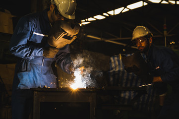 Industrial worker welding metal with many sharp sparks