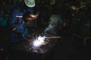 Industrial worker welding metal with many sharp sparks