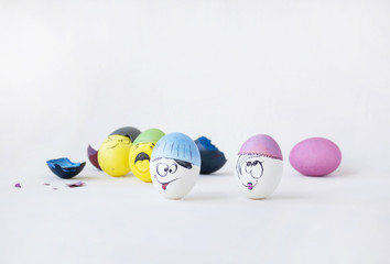 Painted eggs on a white background. Real hand-painted eggs. Multi-faceted photography. The white photo has funny cute faces on the eggs. Holiday and joy of Bright Easter