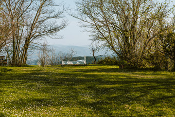 Wide angle shot of a beautiful grassy green lawn with a white single bed in the distance. Relax, isolation, exclusivity, tranquility, serendipity concepts. Vacations. A quite place, warm colors.