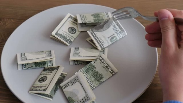 Man eats money dollars in a plate. Concept: food expenses, overeating, dietary expenses, earnings, cooking, restaurateur