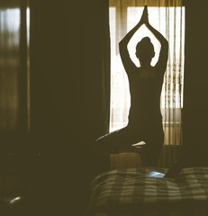 woman in a yoga pose in bedroom staying fit and mentally healthy at home