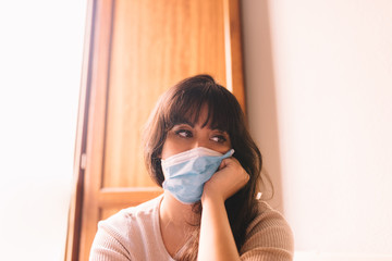 Lonely woman at home in breathing medical respiratory mask on her face, bored woman. Chinese...