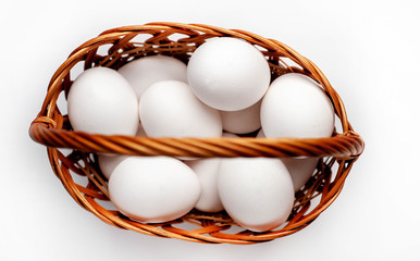 
raw chicken eggs in a basket on a white background