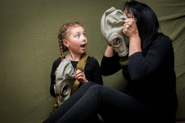 Mom teaches her daughter to put a gas mask on her head. The family in the shelter learn to use...