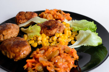 Fried chicken cutlet with potato slices served with tomato cherry and corn salad. Traditional belorussian food - roasted minced meat and potato