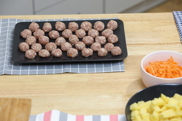 Fresh peeled potato, carrot, lemon and  meat balls on a kitchen table. Preparing for cooking. 