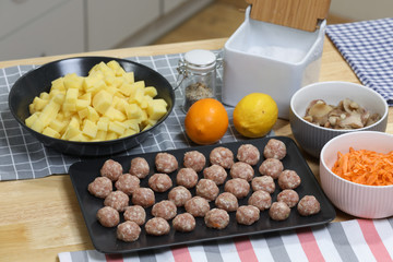 Fresh peeled potato, carrot, lemon and  meat balls on a kitchen table. Preparing for cooking. 