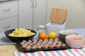 Fresh peeled potato, carrot, lemon and  meat balls on a kitchen table. Preparing for cooking. 