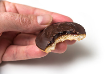 Closeup of crunched  chocolate cakes with jam in hand on white background