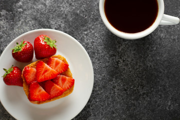 Toast with fresh strawberry and greece cheese on a plate with cup of black coffee. Top view. 