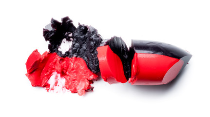 Two-tone lipstick, red and black, broken and crushed isolated on a white background.