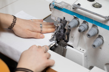 A teenager sews a brown dress on a sewing machine called an overlock.