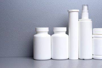 5 white jars for medicines and vitamins and dietary supplements without a name are on a gray shelf. copy space to the left. layout for a pharmacy, a store