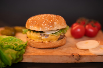 homemade cheeseburger on a wooden Board on a dark background
