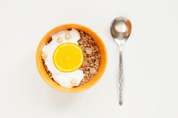 Muesli, granola with yogurt and orange in yellow bowl and spoon on white background 