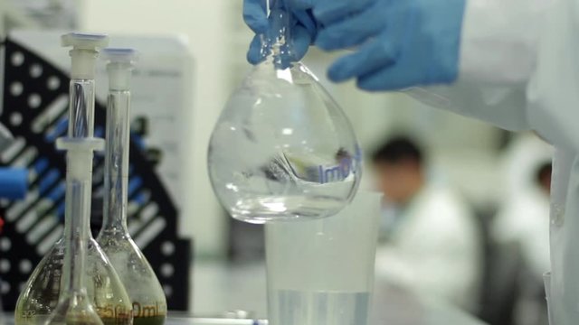 Scientist working with chemical reaction in chemistry lab. Chemical reaction in glass flask. Lab worker doing chemical experiment in laboratory