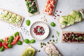 Different kinds of vegetarian sandwiches on a light background. Top view, place for text.