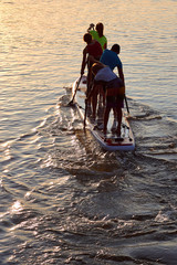Four teenagers row on a large stand up paddle board on the Danube river at summer
