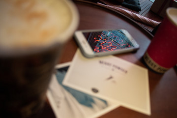 a phone with postcards lies on a table on which there is coffee