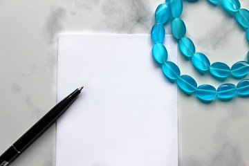 Marble background. Markers blue and a sheet of paper. Sheet for notes, blue theme. Notes of girls and blue beads