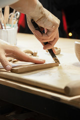 Female hands in clay cut a piece of clay with a knife