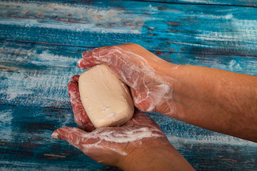 Someone is soaping their hands with a bar of soap on a wooden background. Close up. Regular hand...