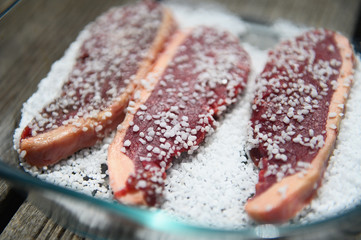 Hand seasoning a piece of raw meat with salt, preparing for a Brazilian barbecue.