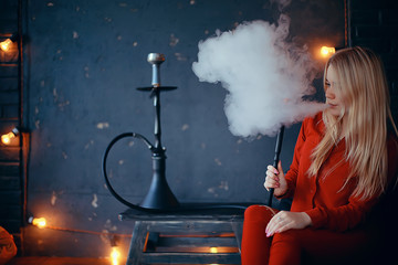 girl smokes hookah / beautiful glamorous girl in red dress smokes a hookah, the sexy model in a night club smokes