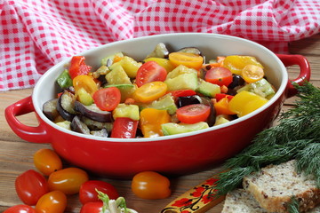 Vegetable stew with eggplant and zucchini on a wooden background