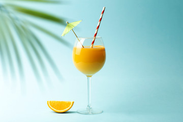Summer drinks concept. Orange juice in a glass cup on a colored blue background. Tropical summer minimal background