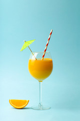 Summer drinks concept. Orange juice in a glass cup on a colored blue background. Tropical summer minimal background