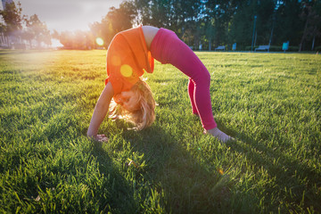 little girl exercise in sunset nature, kid doing gymnastics on grass