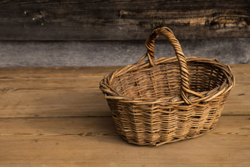 Obraz premium Ancient wicker basket on a wooden background. Selective focus. Free space for text.
